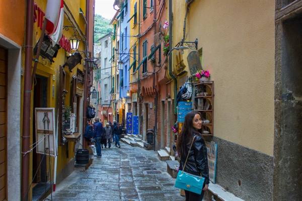 Woman with turquoise bag in a narrow alley of painted colorful houses