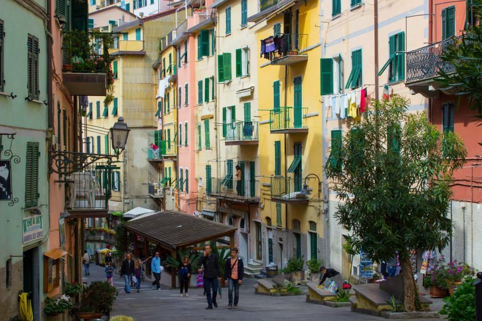 Case colorate con persiane verdi a Vernazza, turisti camminano nella strada