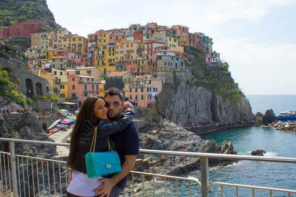Coppia si abbraccia davanti alle case colorate di Manarola sul mare