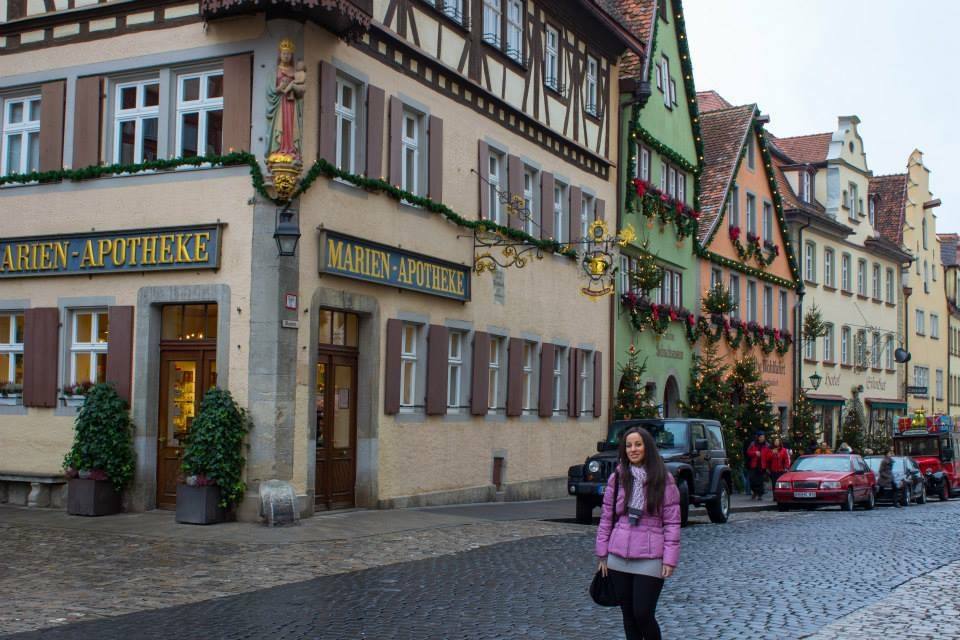 Donna in giacca rosa davanti alla Marien-Apotheke a Rothenburg ob der Tauber