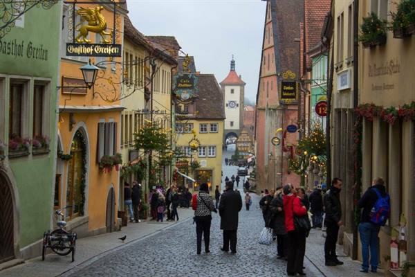Tourists walking on cobbled street among colorful houses in Rothenburg ob der Tauber