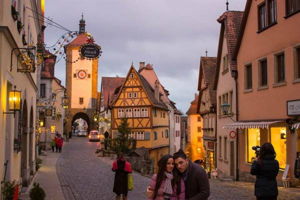 Tourists hug in front of the Markusturm tower in Rothenburg ob der Tauber