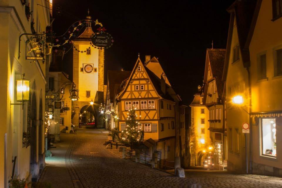 Insegne illuminate e case a graticcio nel vicolo notturno di Rothenburg