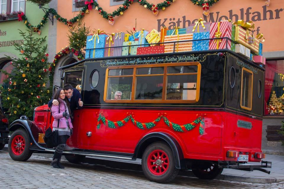 Turisti accanto a un furgone rosso carico di regali davanti al Käthe Wohlfahrt