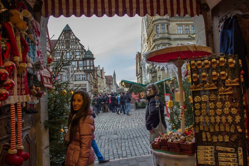 Donna sorridente tra bancarelle natalizie, case a graticcio e ciottoli, Rothenburg ob der Tauber