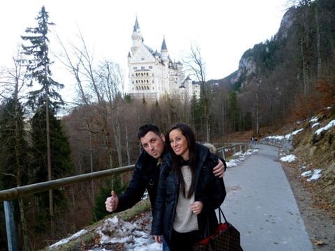 Coppia sorridente sul sentiero innevato davanti al castello di Neuschwanstein