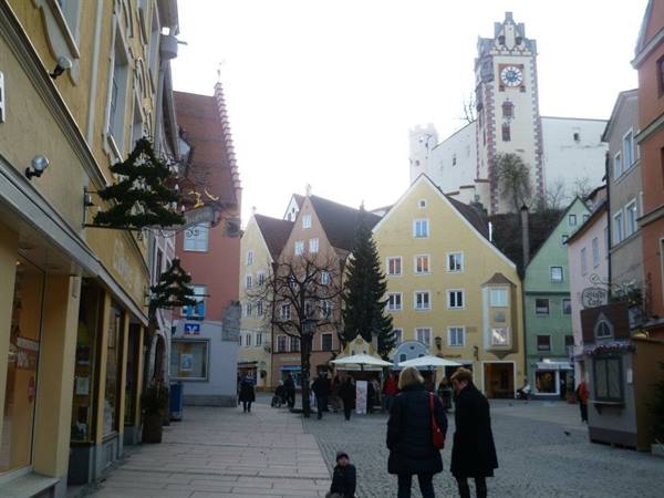 Pedestrian square in Füssen with colorful houses and castle clock tower