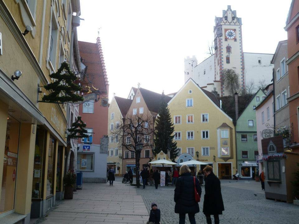 Piazza pedonale a Füssen con case colorate e torre dell'orologio del castello