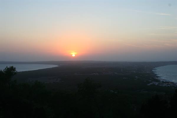 Low orange sun over a headland with sea on both sides