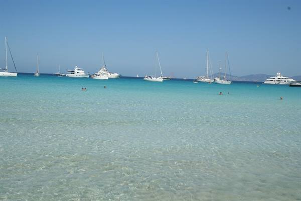 Sailboats and yachts anchored in clear turquoise water, swimmers offshore