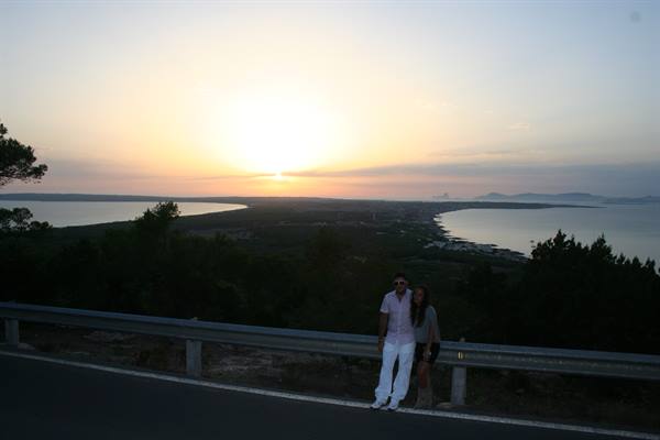 Couple leaning on the guardrail, low sun over sea and coastline
