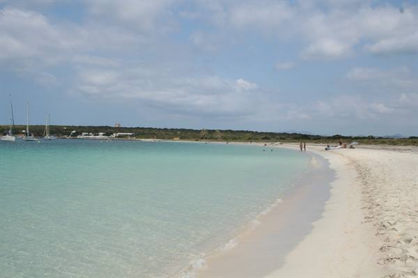 White sand beach, turquoise water, sailboats and swimmers under clouds