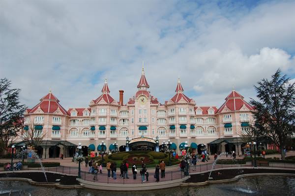 The pink and red Disneyland Paris hotel with visitors in front gardens