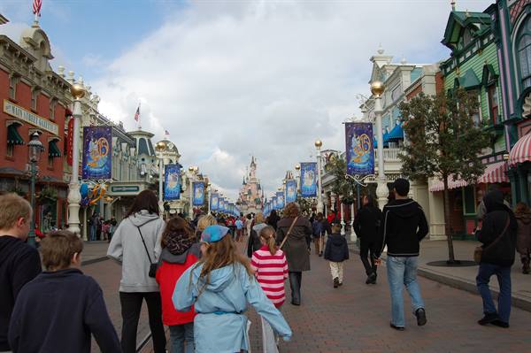 Main Street at Disneyland Paris, visitors walk toward the castle under banners