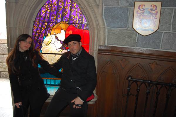 Couple in black beside a princess stained-glass window inside a stone castle