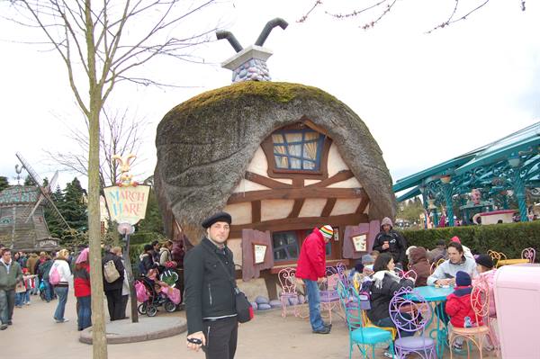 Visitors at colorful tables outside the March Hare cottage, thatched mushroom roof
