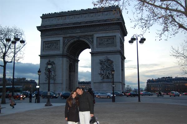 Couple hugging in front of the Arc de Triomphe in Paris at dusk