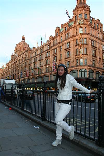 Woman in white leaning on railing in front of Harrods department store
