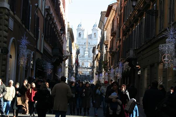 Crowd on Via dei Condotti, Trinità dei Monti church above Spanish Steps in sunlight
