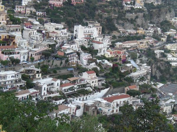 Colorful houses stacked on Positano's rocky hillside among green vegetation