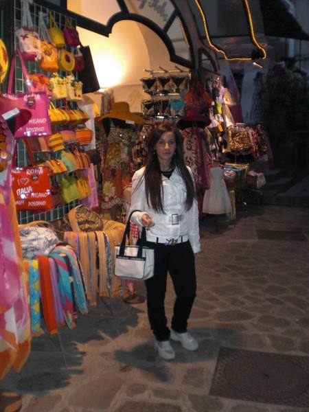Woman in white jacket holding a bag outside a souvenir shop