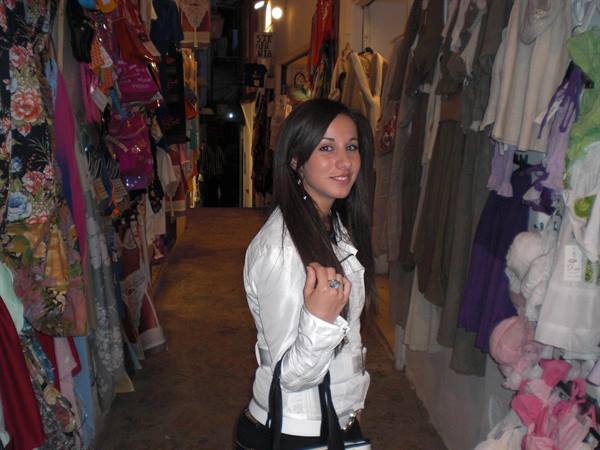 Girl in white jacket among colorful clothes in a covered market