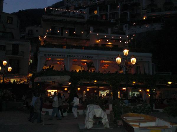 Positano square at night, Buca di Bacco restaurant lights among strolling crowd