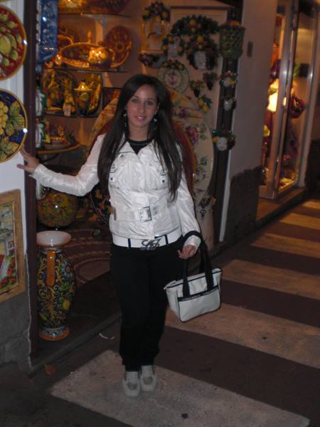 Woman in white jacket beside hand-painted ceramics in a shop
