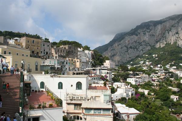 Tourists on a staircase among Capri's white houses beneath the rocky mountain