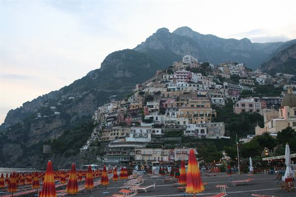 Red umbrellas on the beach below Positano's colorful hillside houses
