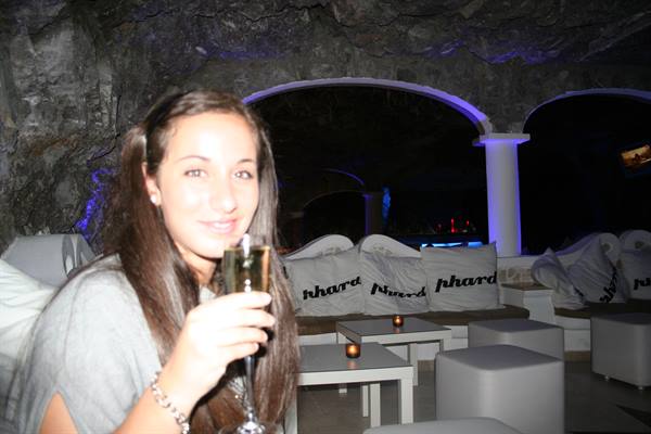Smiling girl raises a champagne glass in the cave lounge with white sofas