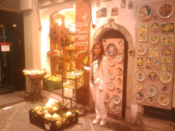 Woman in white outside a ceramics and lemon shop, warm evening light
