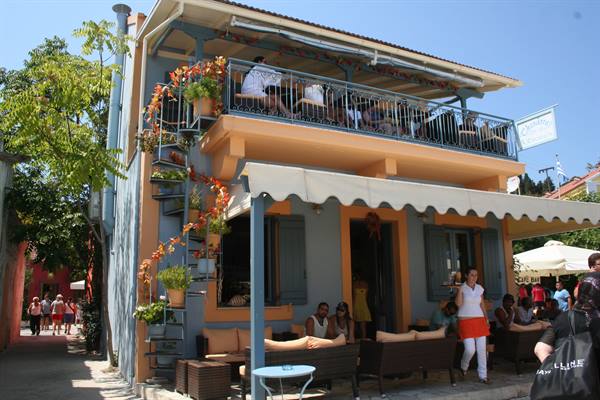 Cafe with wooden balcony and flowers, customers sitting under the awnings