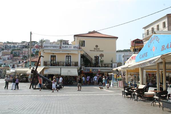 Harbor square in Pythagoreio with ancient anchor, cafes and tourists