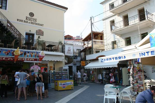 Tourists outside an ice cream shop and Rudis wine bar on a Greek street
