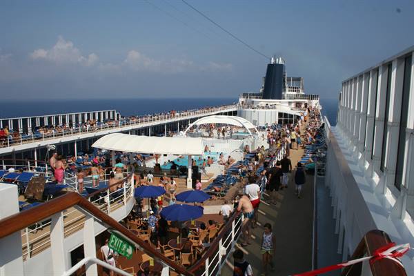 Cruise ship decks crowded with passengers, pool area and blue umbrellas
