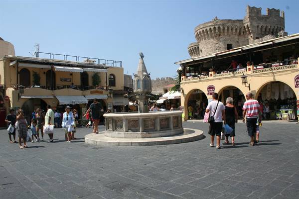 Tourists stroll around the fountain of Hippocrates in Rhodes old town square