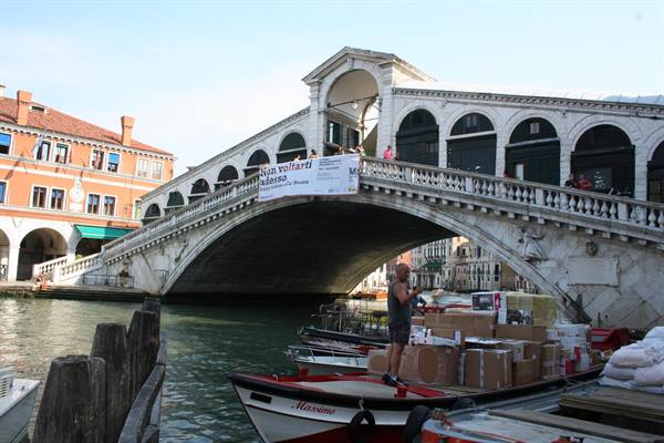 Rialto Bridge in Venice, man on boat loaded with boxes delivering packages