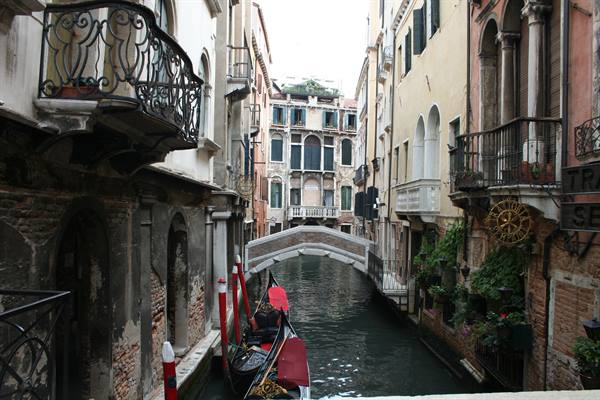 Gondolas moored beside a small bridge over a canal between old palaces, Venice