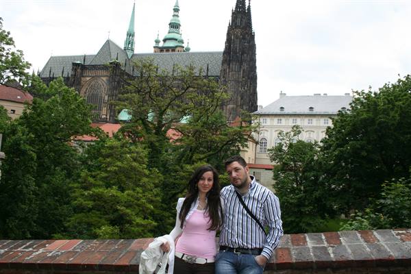 Couple leaning on a brick wall in front of Prague's St. Vitus Cathedral