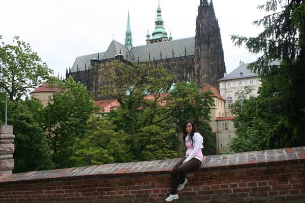 Girl sitting on brick wall in front of St. Vitus Cathedral