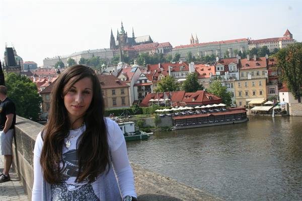 Girl on Charles Bridge, Prague Castle and Vltava river behind