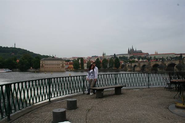Couple on Prague riverside promenade, castle and Charles Bridge in the background