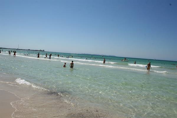 Swimmers in turquoise waves under a clear blue sky