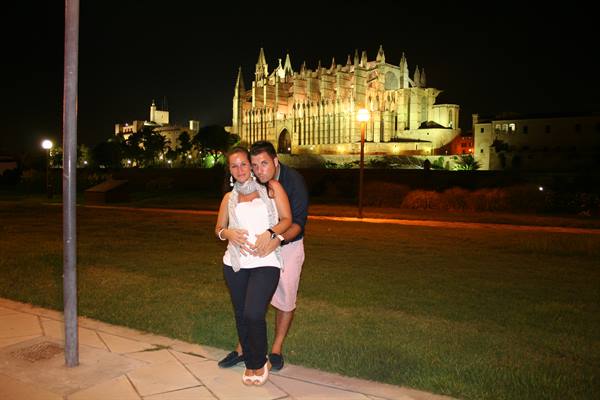 Couple hugging at night in front of the illuminated Palma de Mallorca cathedral