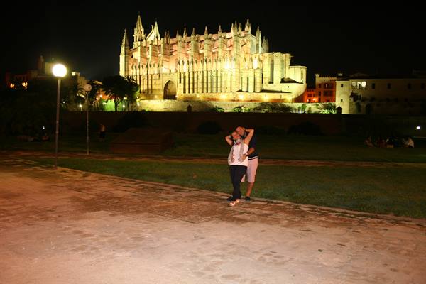 Couple embracing at night in front of the illuminated Palma de Mallorca cathedral