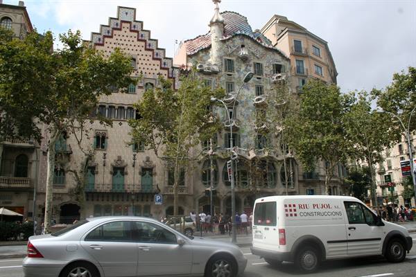 Casa Batlló facade in Barcelona behind traffic and street trees