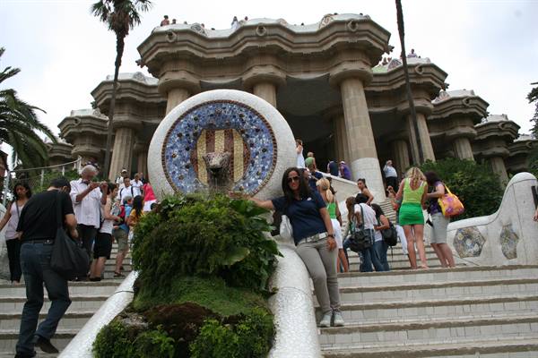 Tourists on the mosaic fountain staircase at Park Güell, Gaudí's hypostyle hall behind