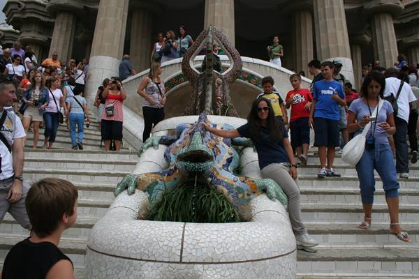 Tourist posing by Gaudí's mosaic lizard, Park Güell, Barcelona