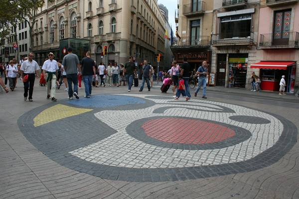 Tourists walk beside the Miró mosaic pavement on La Rambla, Barcelona